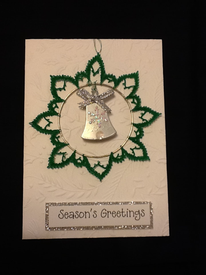 Christmas card with a green lace decoration and gold bell